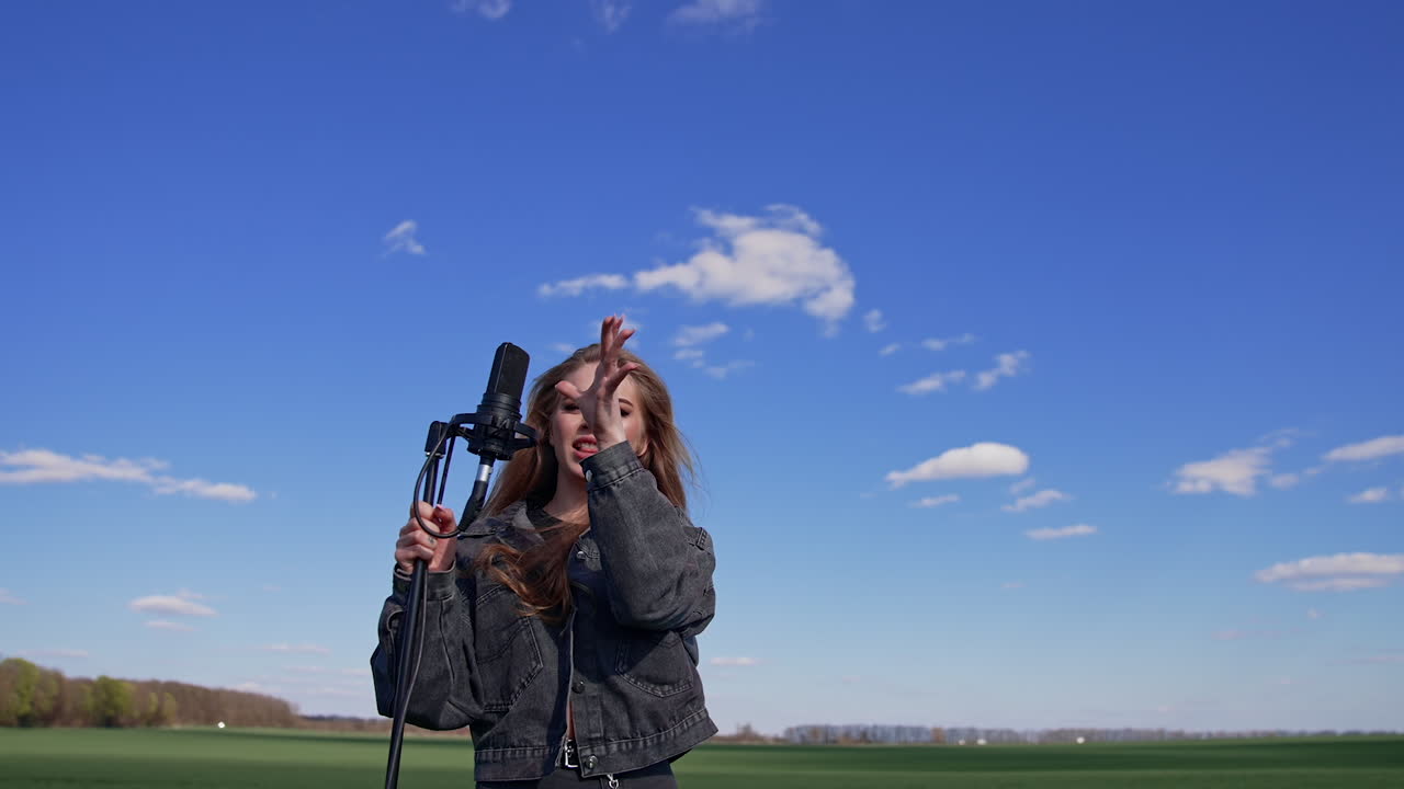 Girl singing with microphone on nature. Young woman singing with microphone on nature
