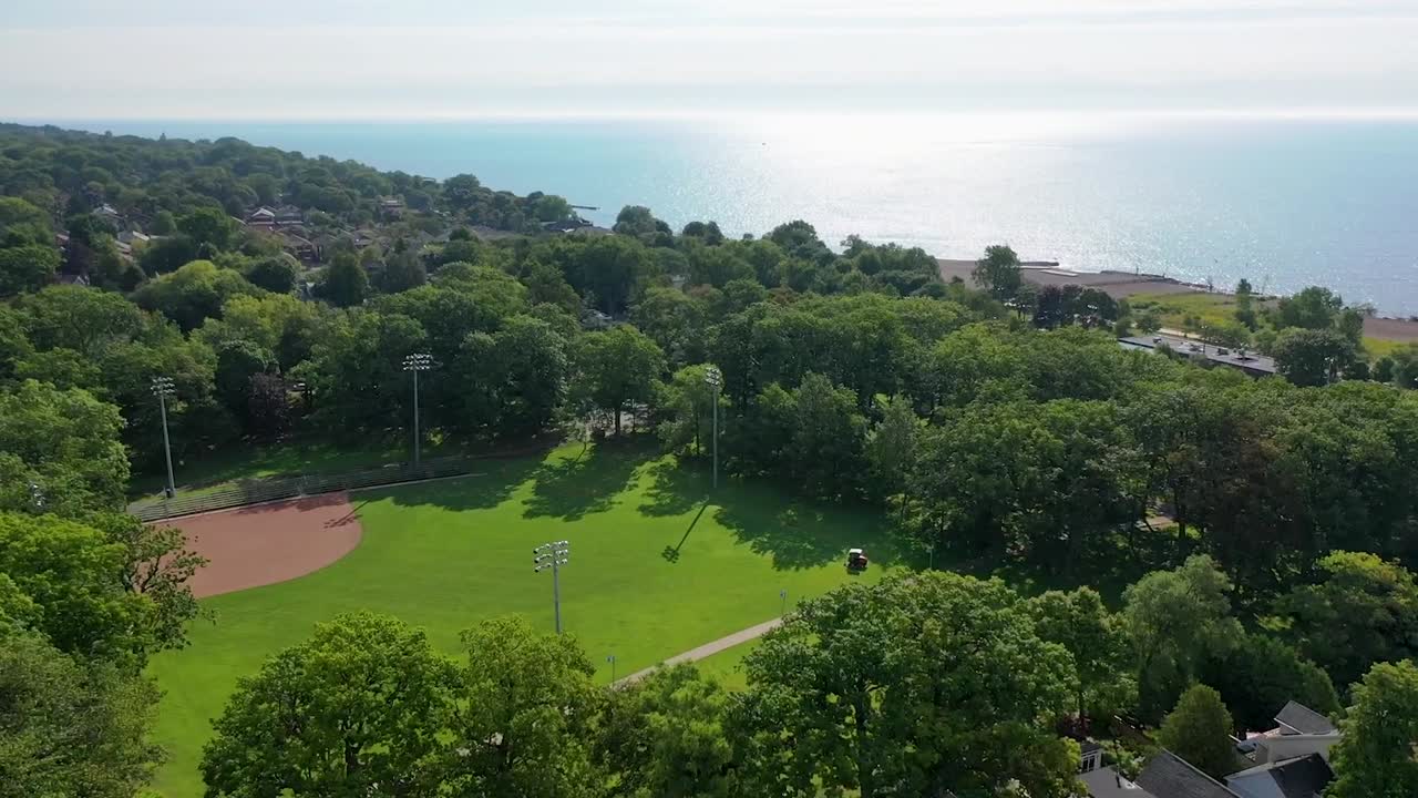 drone volando alrededor del diamante de béisbol en el verano cerca del lago ontario y toronto