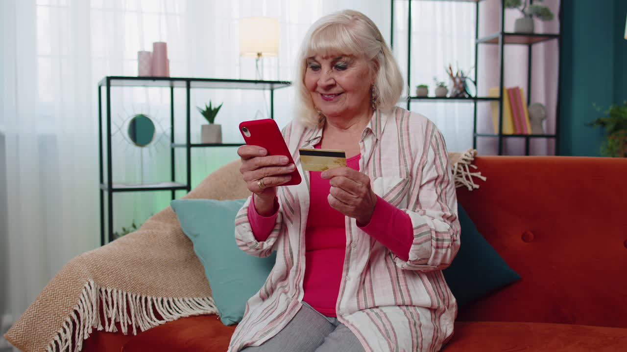 고령 여성은 신용카드를 들고, 휴대전화에 번호를 입력하고, 온라인 쇼핑을 하고, 상품을 구입합니다.