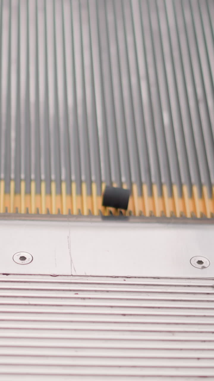 el objeto negro gira en la escalera mecánica en movimiento a medida que sube, las marcas amarillas en los lados de la pared de la escalera eléctrica son visibles, con el lugar hacia arriba, enfatizando el aspecto mecánico y de movimiento de la escena