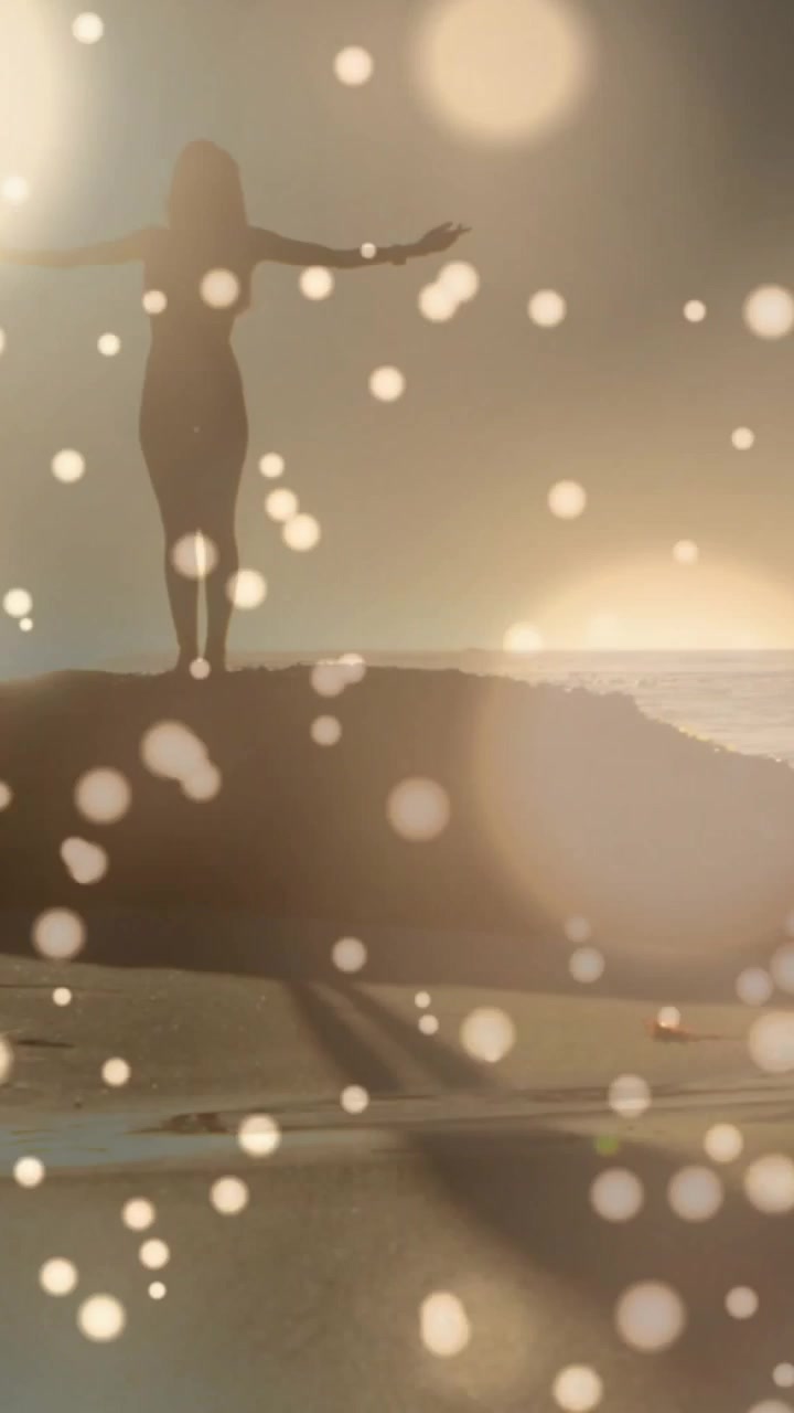 Vertical video: Sunset sparking figure stepping onto rock, turning, raising arms to greet sun