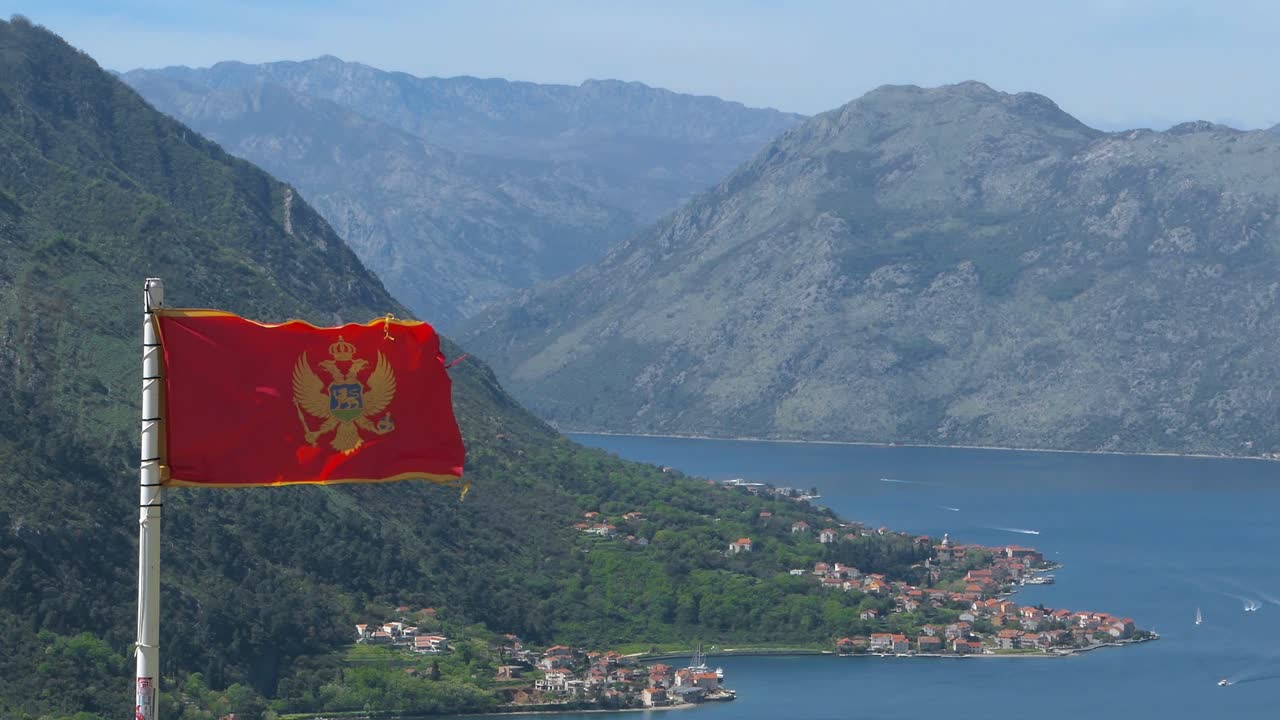 Flag of Montenegro waving in the wind, Kotor Bay, Boka, mountain range and sea