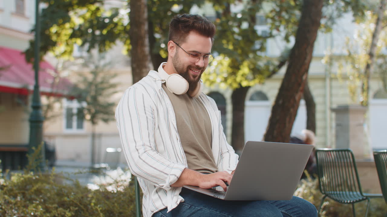 Caucasian young man freelancer working online distant job using laptop sitting on city town street