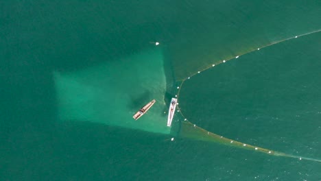 vista aérea de arriba hacia abajo del pescador colocando la trampa de red para atrapar peces sobre la superficie del agua en el océano