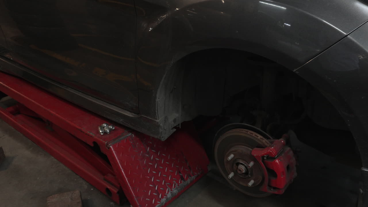 Close up of a vehicle brake system on a jack without wheels in a garage