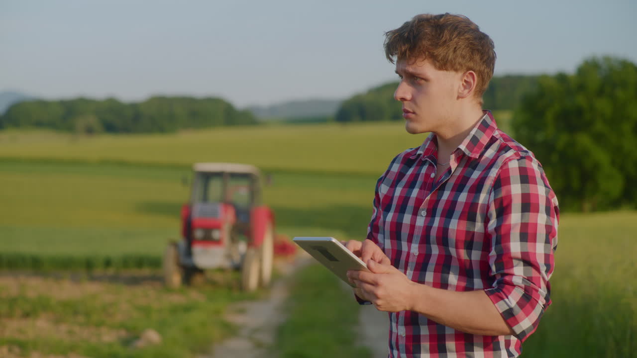 Bauer benutzt digitales Tablet während der Ernte auf dem Feld