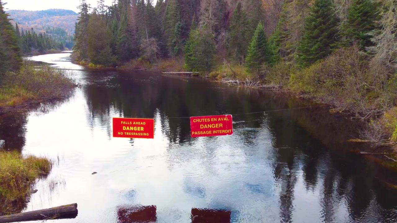 Danger sign over the river somewhere at Mont Tremblant forests, Québec, Canada.