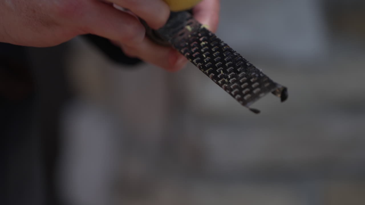 제스터로 레몬 제스트를 손으로 갈고 있습니다.