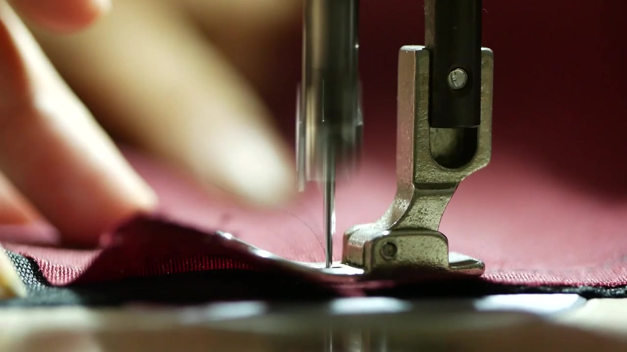 4K close-up footage of a sewing machine in operation, capturing stitching movement, fabric detail, and industrial or home tailoring process.