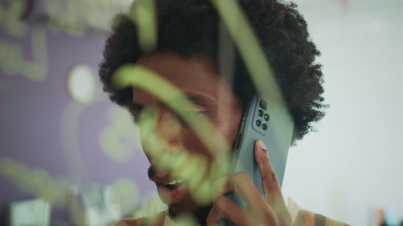 Startup Owner Talking on Cellphone and Writing Ideas on Glass Wall