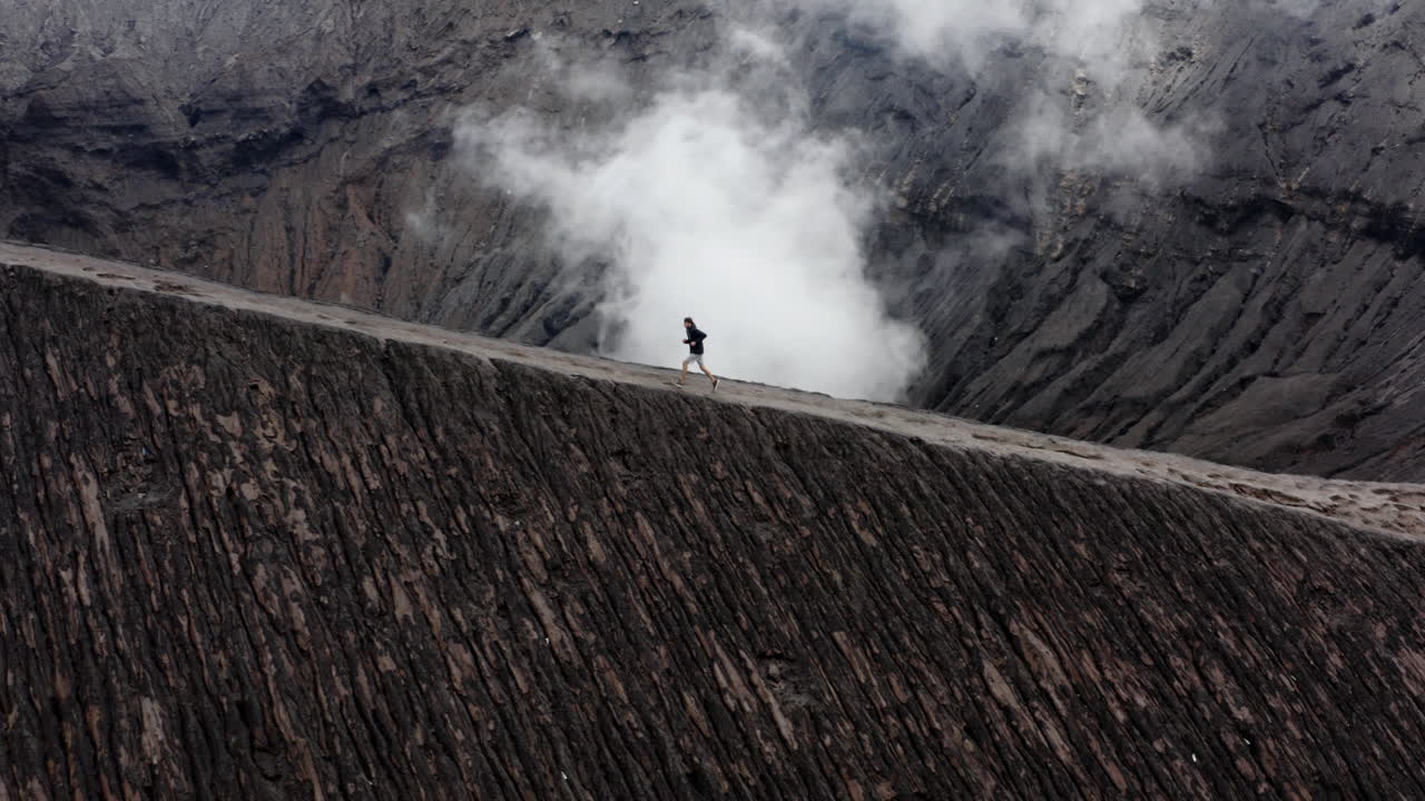 Active man running on edge of billowing Volcano in Indonesia