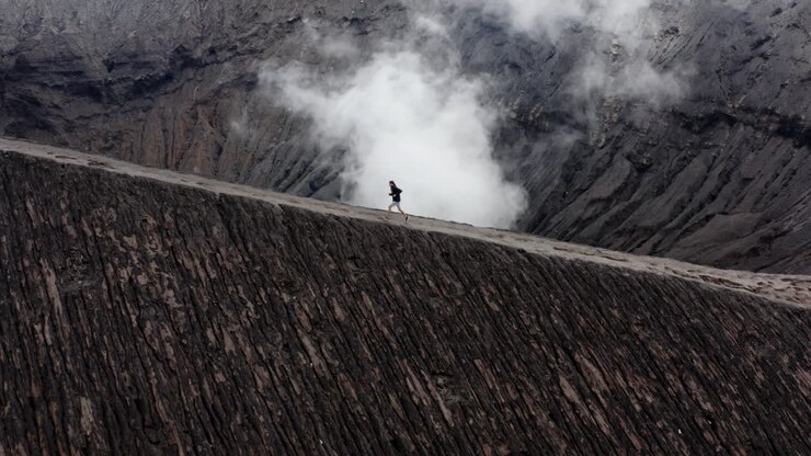Active man running on edge of billowing Volcano in Indonesia