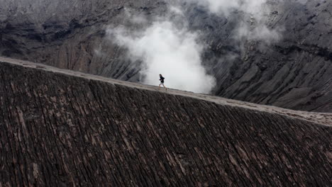 active man running on edge of billowing volcano in indonesia