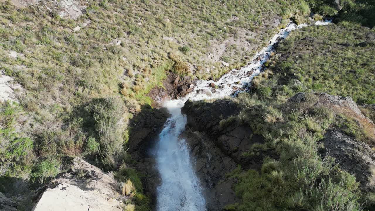 Aerial descends remote Caryacuyo waterfall in arid mtns of south Peru