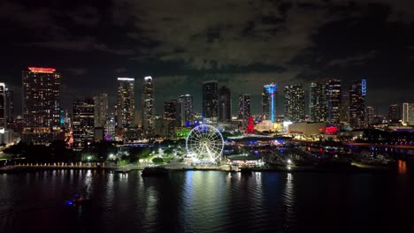 Vista-Aérea-Lejana-Del-Centro-De-Miami-Con-El-Paseo-Marítimo,-El-Puerto-Deportivo-Y-La-Noria-Por-La-Noche