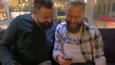 Close-up-view-of-two-white-mature-bearded-men-using-smartphone-together