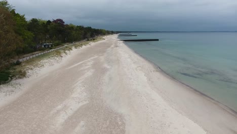 toma aérea de ystad saltsjöbad en el sur de suecia skåne cerca del océano östersjön con gente corriendo por la playa en un día nublado