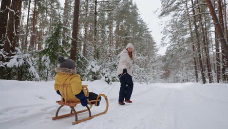 Eine-Junge-Mutter-Und-Ihr-Sohn-Vergnügen-Sich-Im-Winter-Beim-Schlittenfahren-Im-Wald-In-Zeitlupe.-Glückliche-Mutter-Auf-Einem-Spaziergang-Mit-Ihrem-Sohn-In-Einem-Verschneiten-Wald