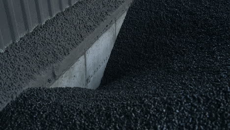 charcoal storage at the agricultural grain elevator. black charcoal pieces go down to the hearth to heat the grain storage. close up.