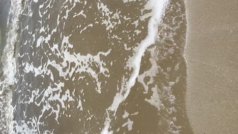 espuma con olas del mar en la playa desde una vista de tiro vertical