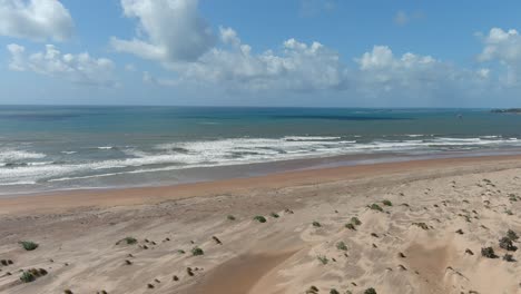 Imágenes-De-Drones-Descendentes-A-Una-Hermosa-Playa-Grande-Con-Arena-Marrón-Clara-En-Un-Océano-En-Calma