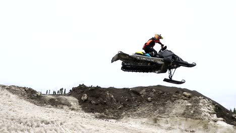 a guy is jumping very high with his snowmobile during a race