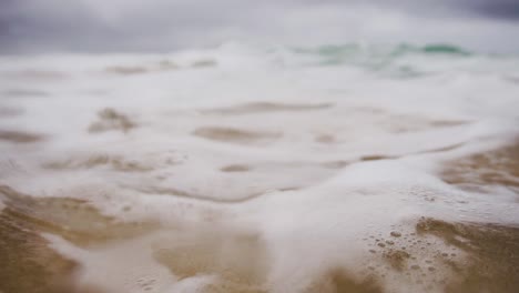 burbujas de agua verde espumosa entre olas en un día nublado y sombrío en el océano