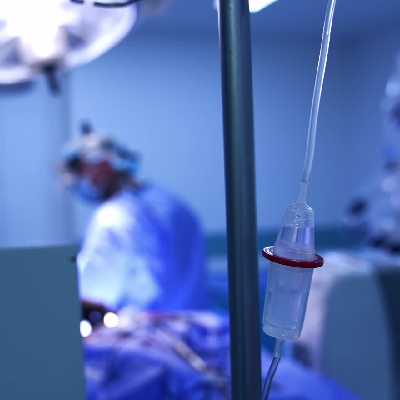 Un operatore con un contagocce e dei farmaci durante un'operazione. Team di medici che lavora in sala operatoria sullo sfondo in modo sfocato