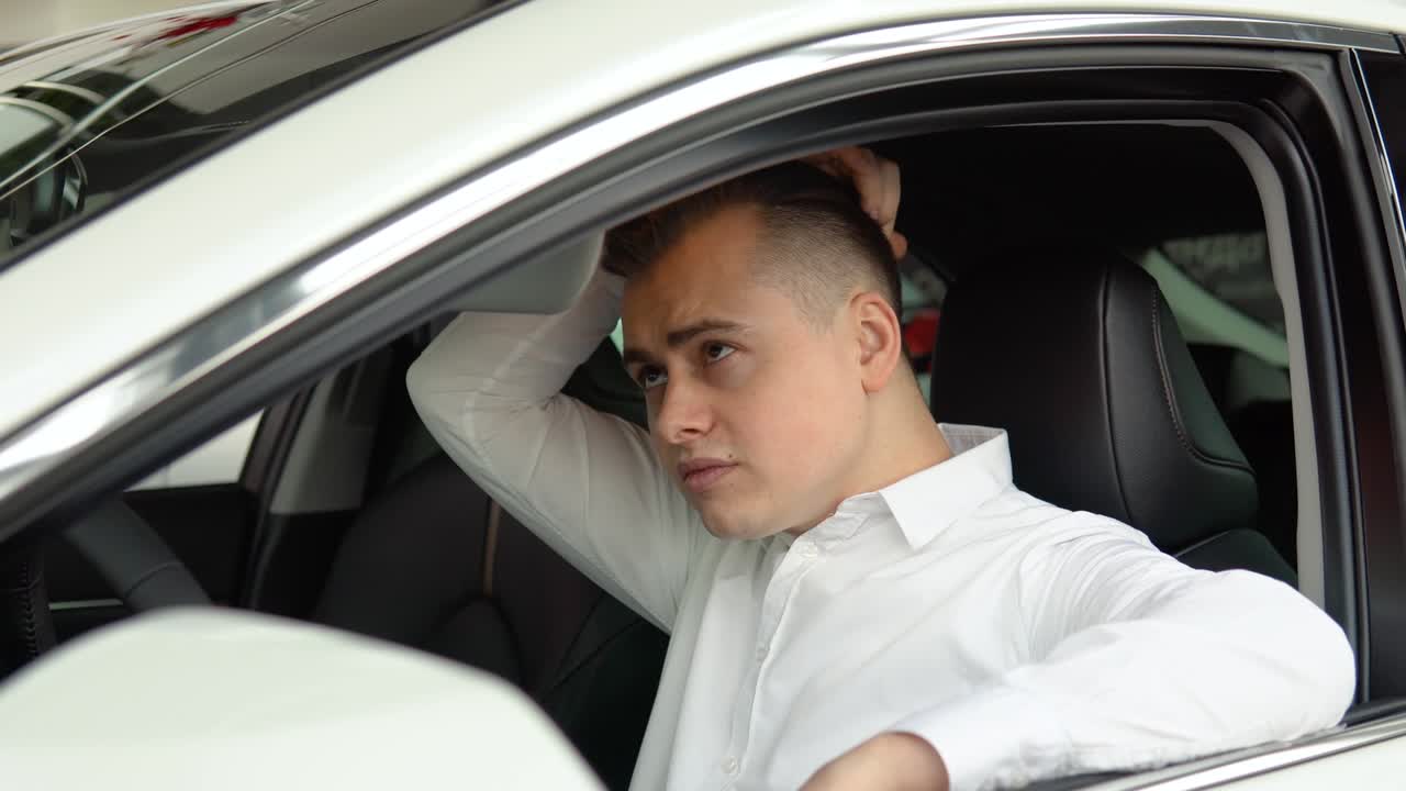 Portrait of a young confident man sitting in a new car at a car dealership