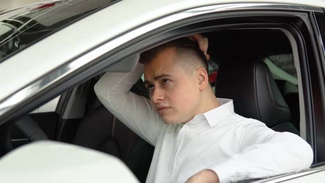 portrait of a young confident man sitting in a new car at a car dealership