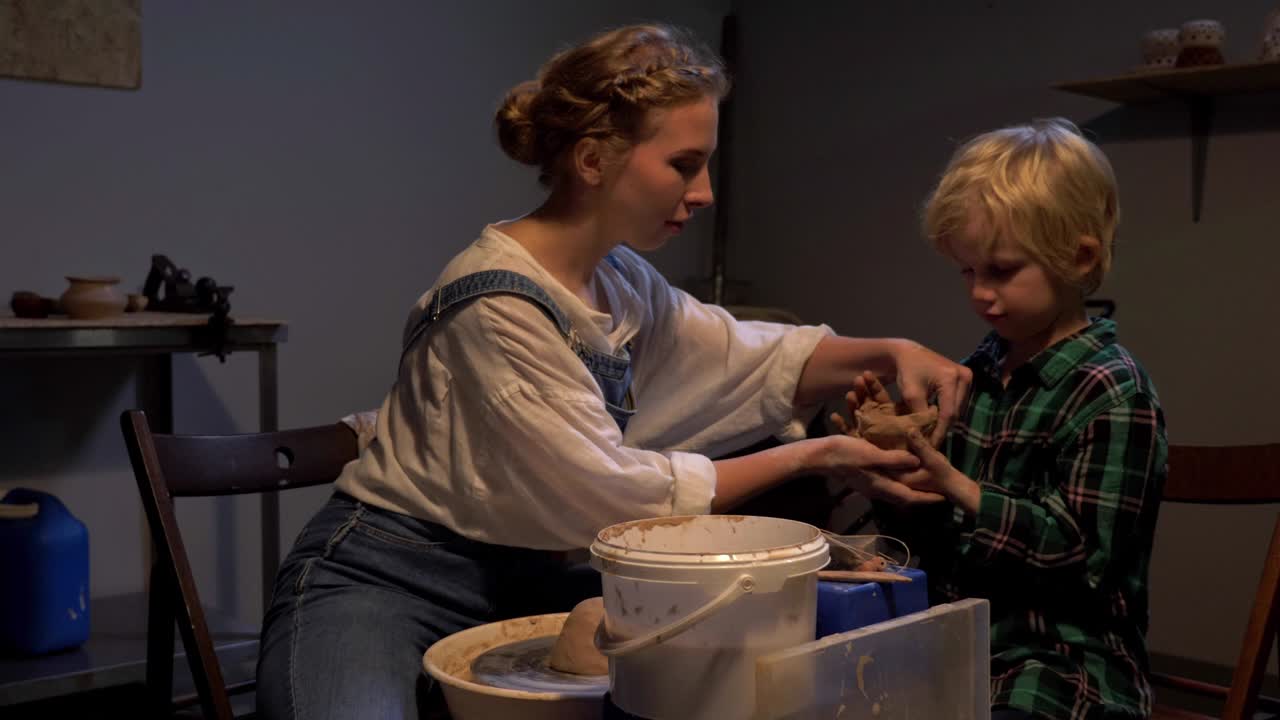 cámara lenta, la mujer ayuda al niño a esculpir en el taller