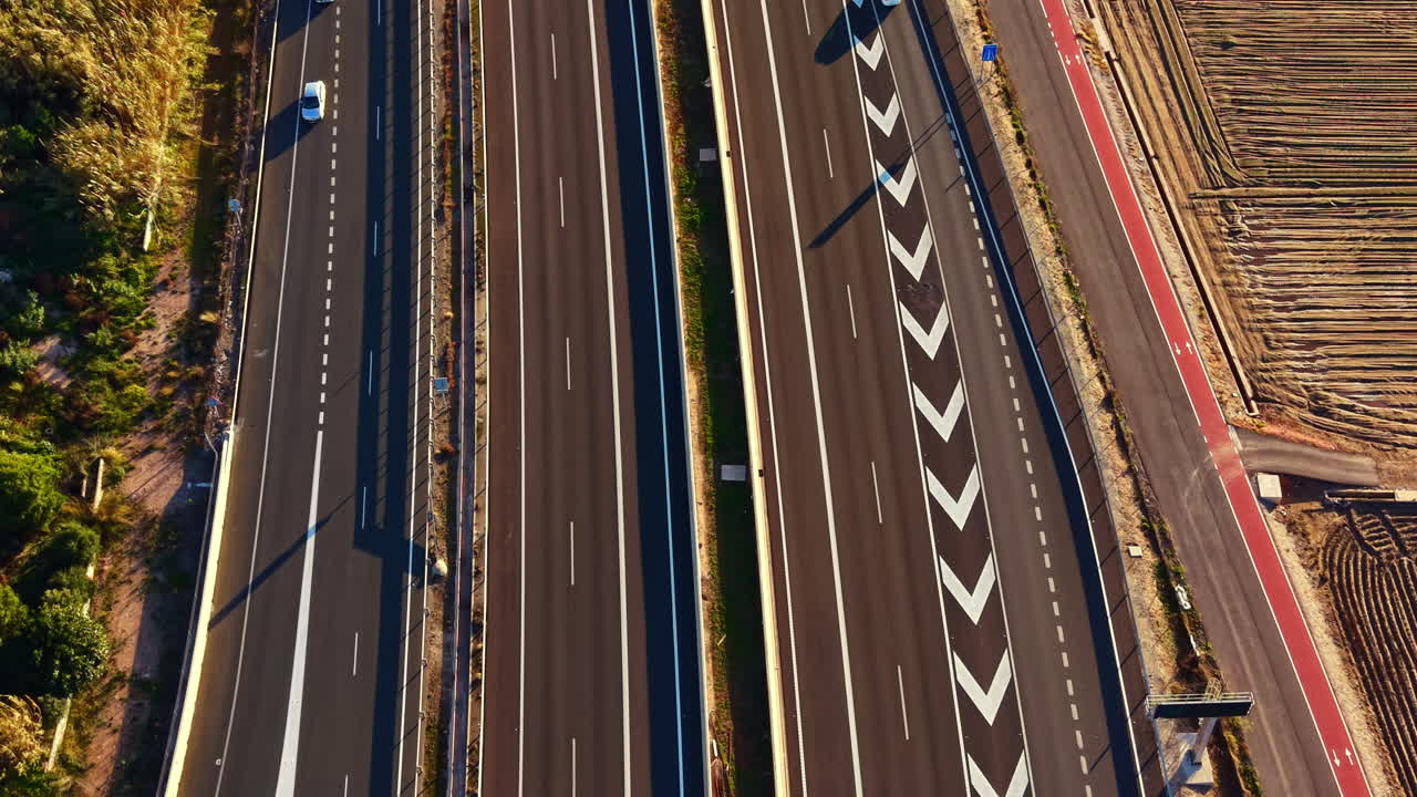 Il traffico scorre su un'autostrada in una zona rurale con veicoli che viaggiano in entrambe le direzioni durante una giornata di sole.