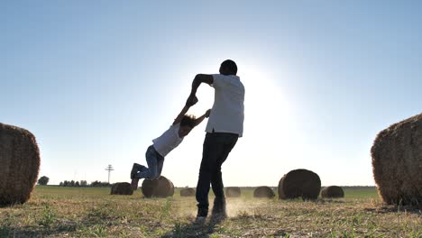 padre sonriente dando vueltas a su hija entre pilas de paja