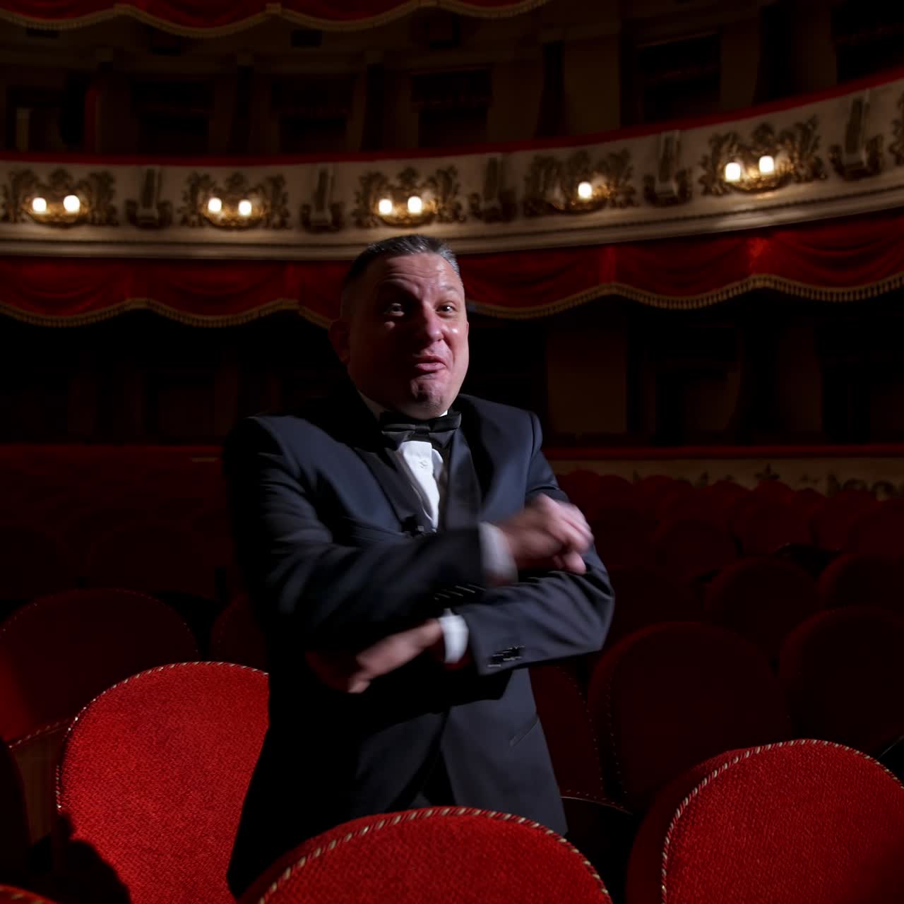 Happy actor puts off medical mask and throws it. Man in costume sitting in the empty theatrical hall and invites joyfully to come to performance. The end of pandemic