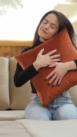 woman tests a store couch before buying hugging a pillow and feeling relaxed young woman is testing out furniture in a store sitting on a couch and hugging a pillow she looks comfortable and relaxed preparing to make a purchase decision