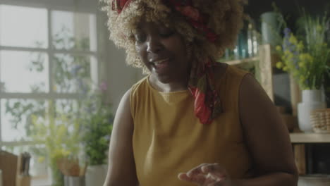 woman with curly hair and headscarf in a plant-filled room