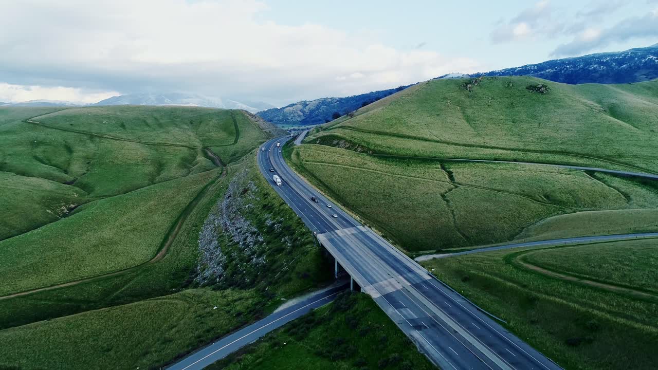 Highway crossing green hills in rural California, peaceful aerial travel moment