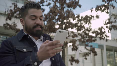 hombre sonriente usando teléfono celular en la calle