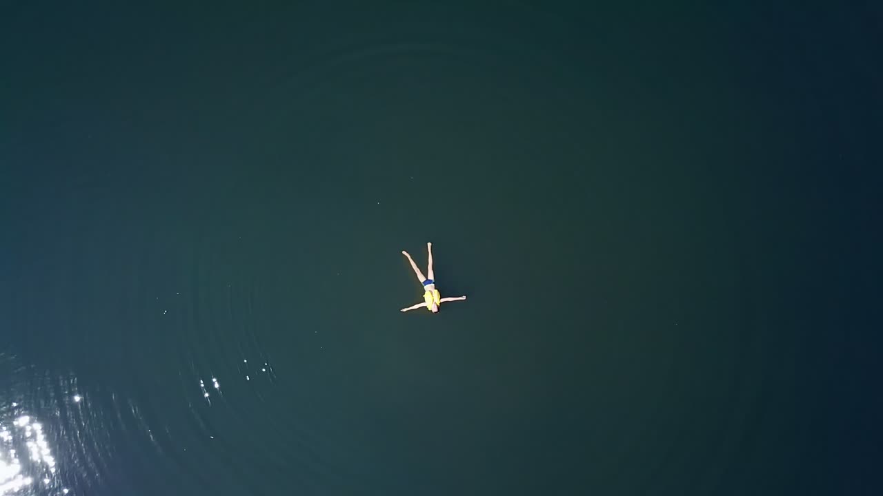 Boy swimming in river. Aerial drone bird eye view of boy relaxing in river