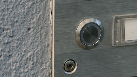 Static-close-up-shot-of-a-doorbell-while-trying-to-ring-several-times-until-someone-opens-the-door