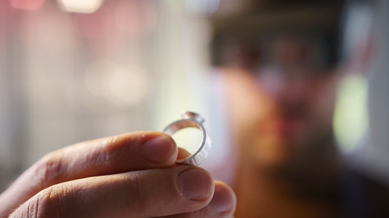 Close Up Of Male Jeweller Looking At Ring Through Headband Magnifiers In Studio