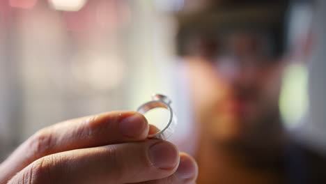 close up of male jeweller looking at ring through headband magnifiers in studio