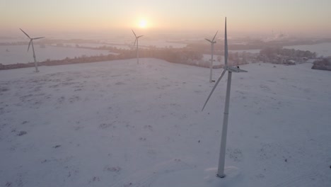 a rotating windmill as an energy generator is located in northern germany near the a1 motorway, sunset snowy landscape