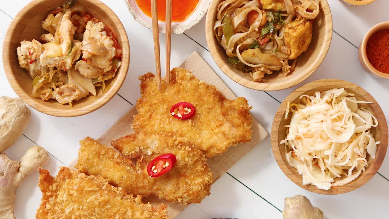 흰색 나무 테이블에 샐러드 향신료를 곁들인 빵가루에 튀긴 바삭한 치킨