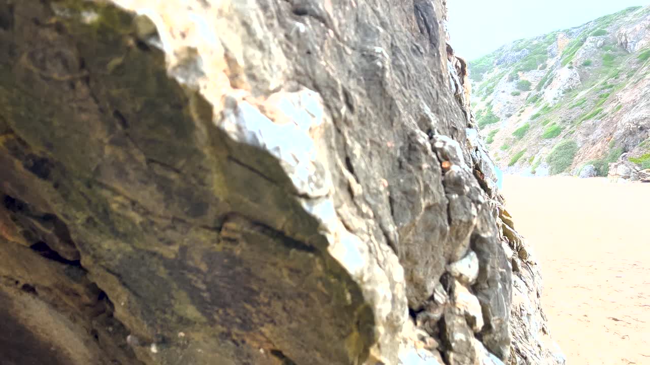 포르투갈 의 싱트라 카스카이스 의 그림 같은 풍경 을 배경 으로 한 프라야 다 아드라가 의 모래 해변 의 바위 와 절벽 의 부드러운 근접 시선