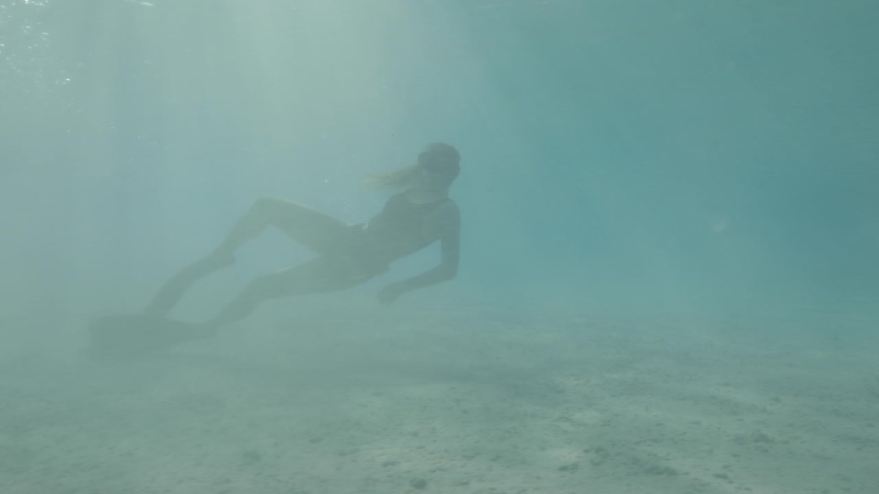 niña buzo libre nadando en el mar rojo rodeada de corales y vida marina con la magia de la luz solar tomada en perfil en color estilo cine crudo