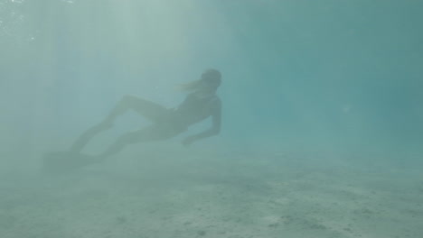 niña buzo libre nadando en el mar rojo rodeada de corales y vida marina con la magia de la luz solar tomada en perfil en color estilo cine crudo