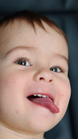funny playful baby boy sits in office chair. cute kid shows tongue to camera. close up. vertical video