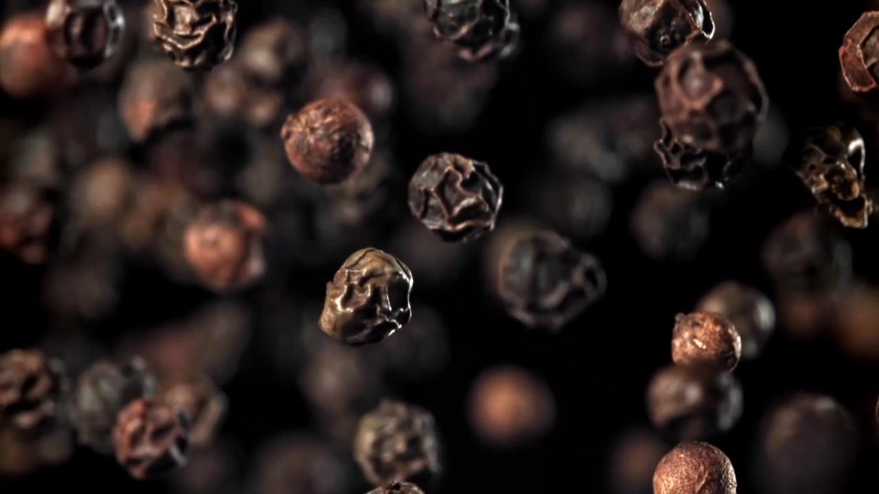 Svarte pepperkorn faller i super sakte film på en mørk bakgrunn