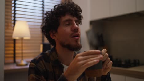 hombre bebiendo una bebida caliente en una cocina acogedora
